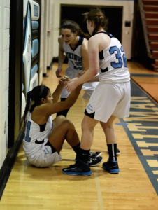 Guard Hannah Niles is helped up by her teammates after scoring while getting fouled. Niles went on to score eight points in the game. Photo by Michelle Jarcho. 