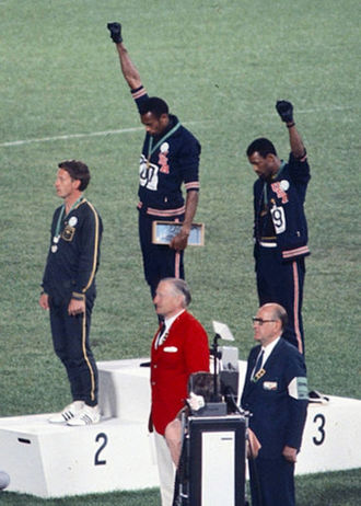 Tommie Smith (center) and John Carlos (right), protested racism in the United States by raising black gloved fists as the national anthem played during their medal ceremony at the 1968 Olympics. The U.S. Olympic Committee expelled Smith and Carlos from the Games as punishment for their actions. It was the first major race-related protest at a sporting event, paving the way for recent athletes’ protests. Photo courtesy Wikimedia Commons.